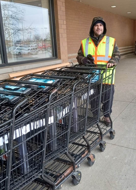 Man working at grocery store collecting shopping carts