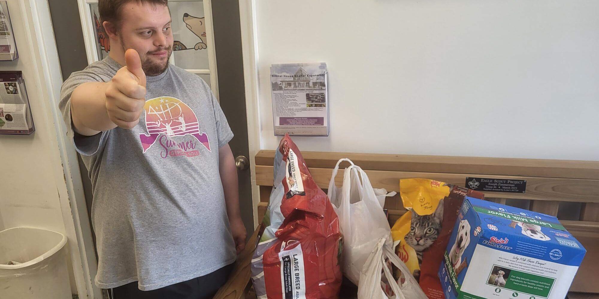 Man giving a thumbs-up in front of donations to the Animal House