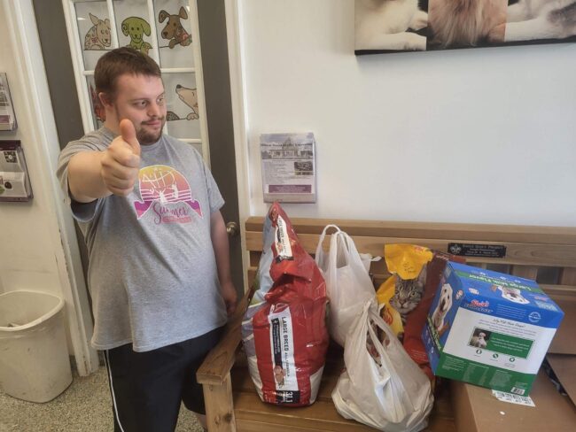 Man giving a thumbs-up in front of donations to the Animal House