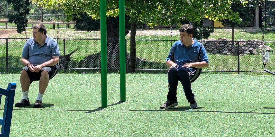 Two men sitting on swings