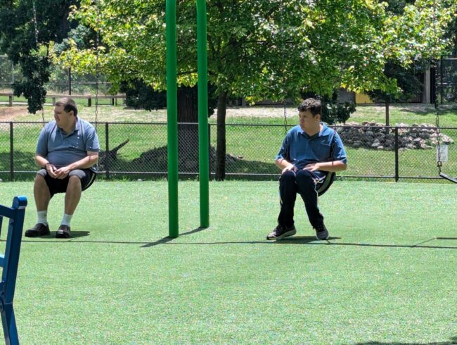 Two men sitting on swings