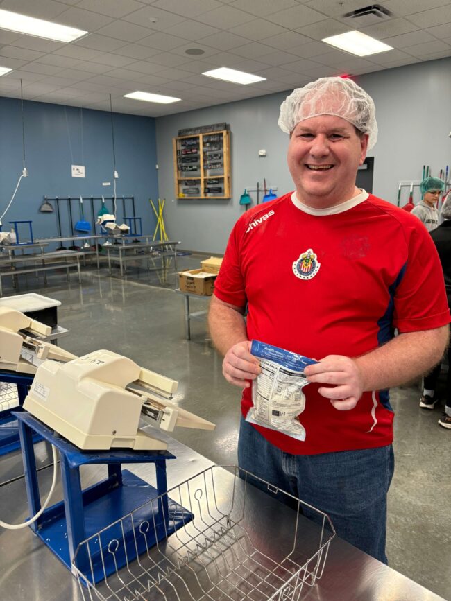 Individual volunteering by heat sealing rice meals at Feed My Starving Children