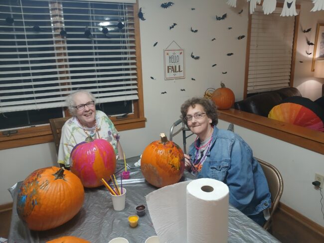 Women posing with their painted pumpkins