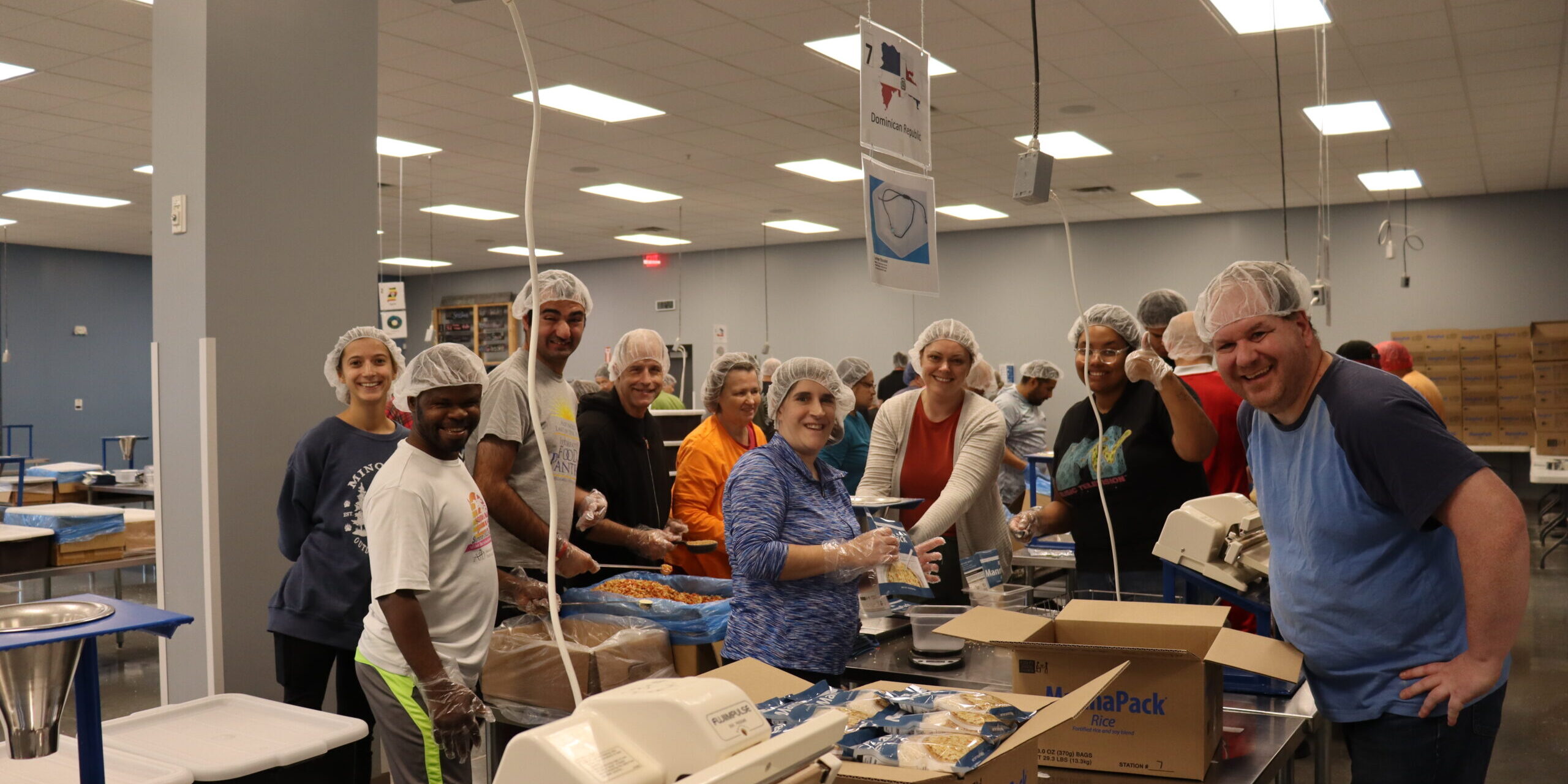 Individuals posing for a picture while volunteering making rice meal packs at Feed My Starving Children