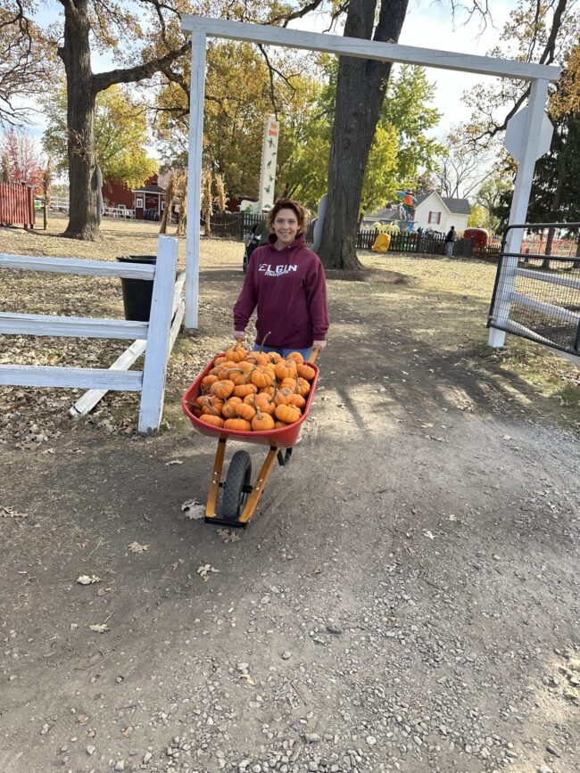 IMG_8119 Woman wheeling a wheelbarrow full of mini pumpkins