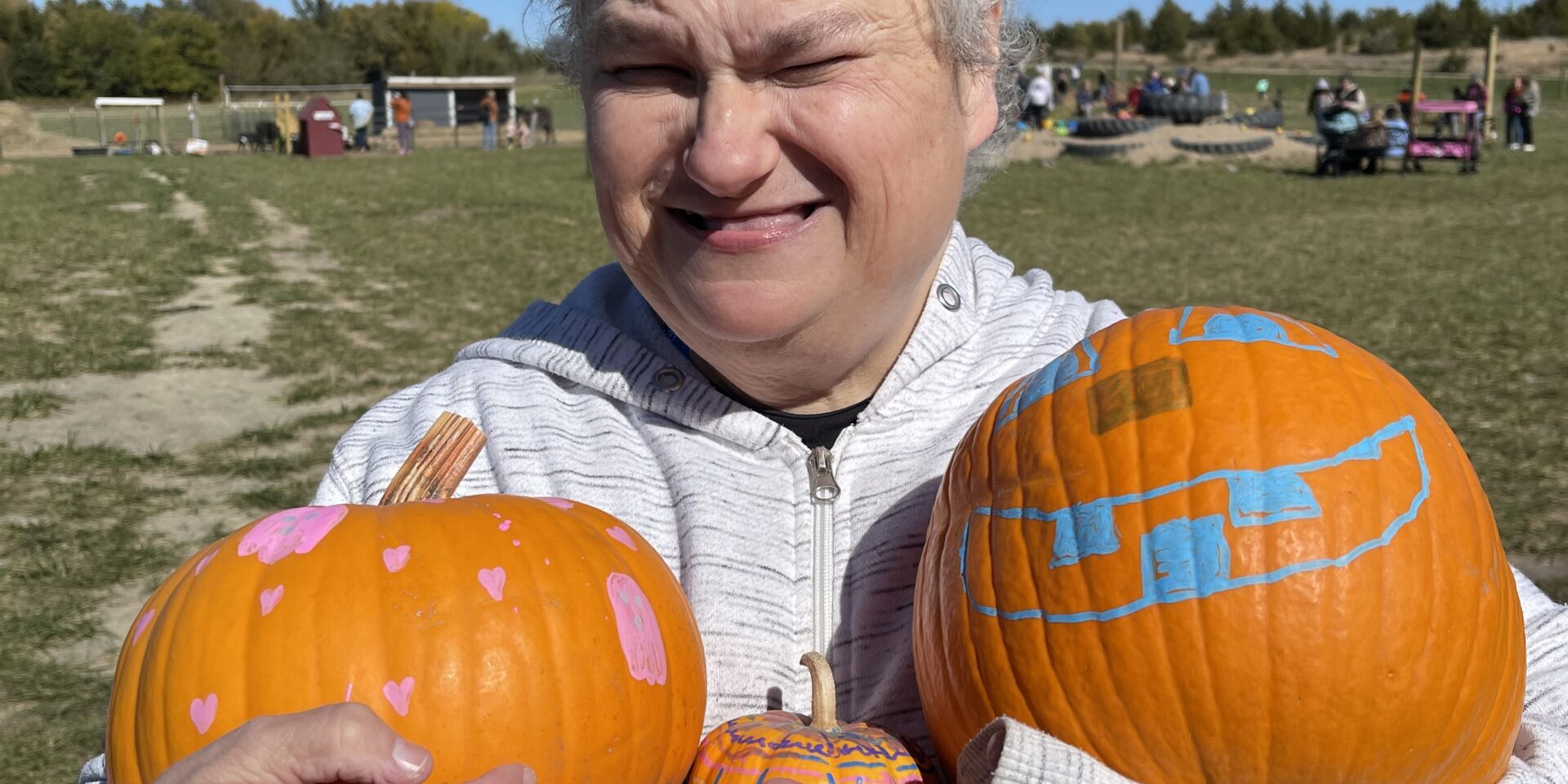 Individual holding three painted pumpkins