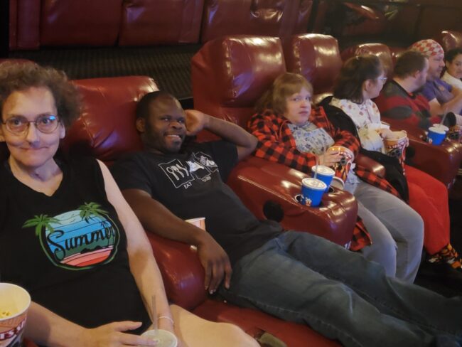 Resized_20241022_110941 Individuals relaxing with popcorn and drinks in movie theater chairs