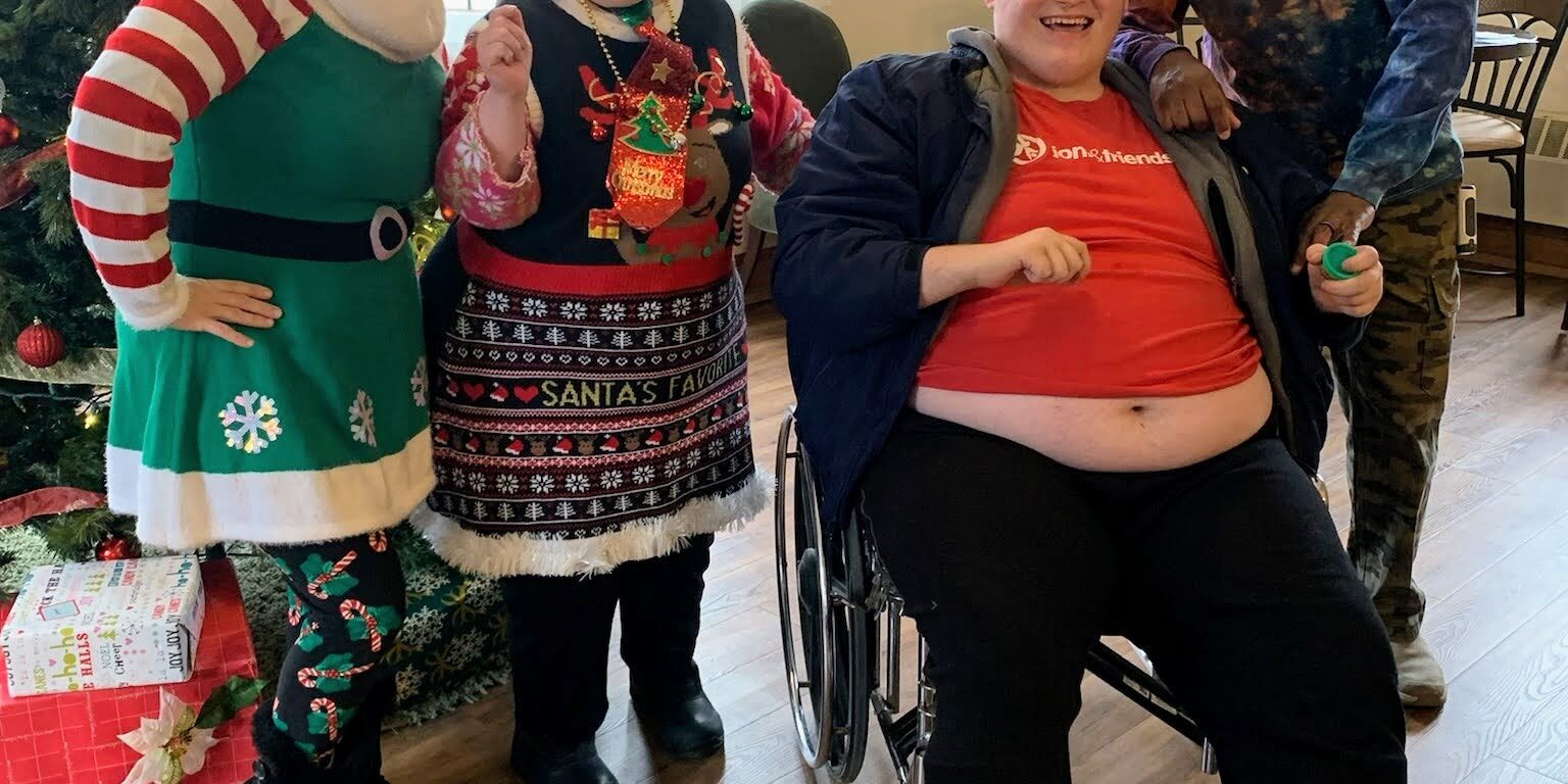 Four individuals pose in front of a Christmas tree