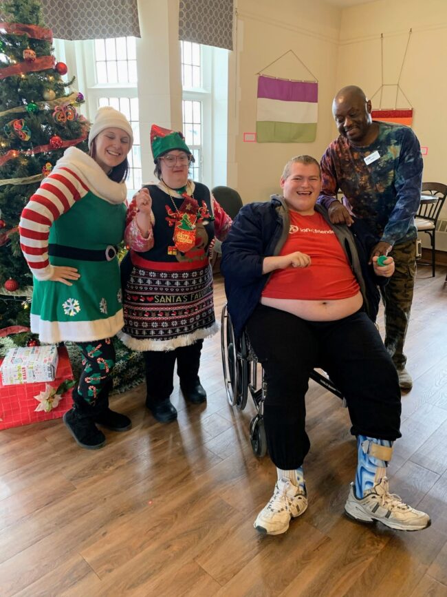 Four individuals pose in front of a Christmas tree