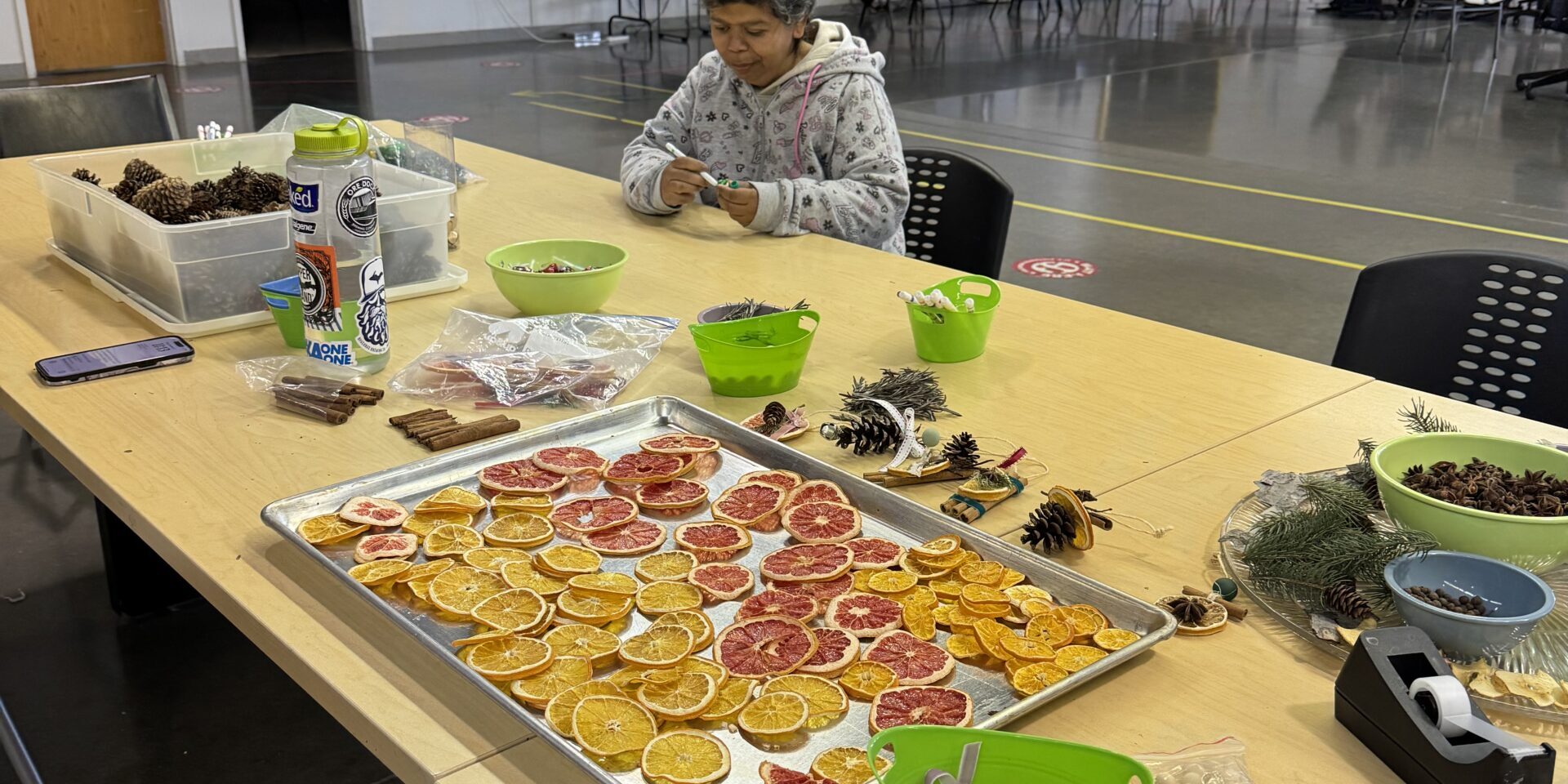A woman sitting at a table with sustainable ornament craft supplies