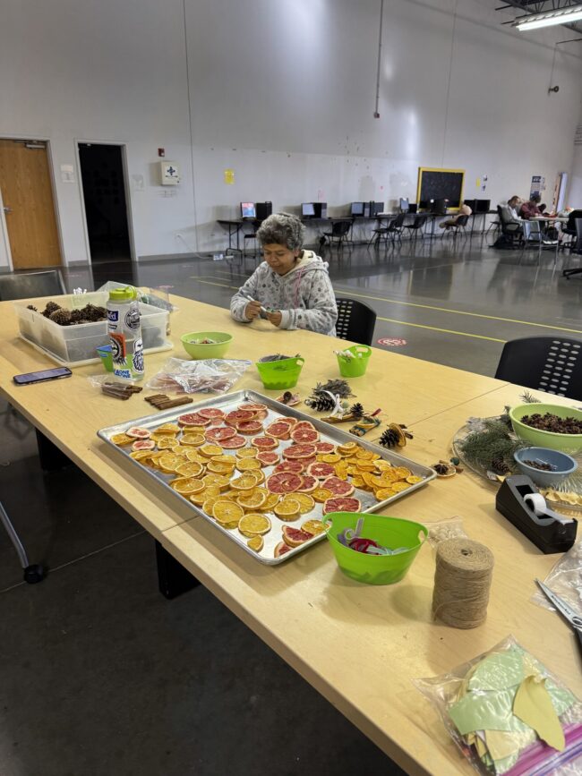 A woman sitting at a table with sustainable ornament craft supplies