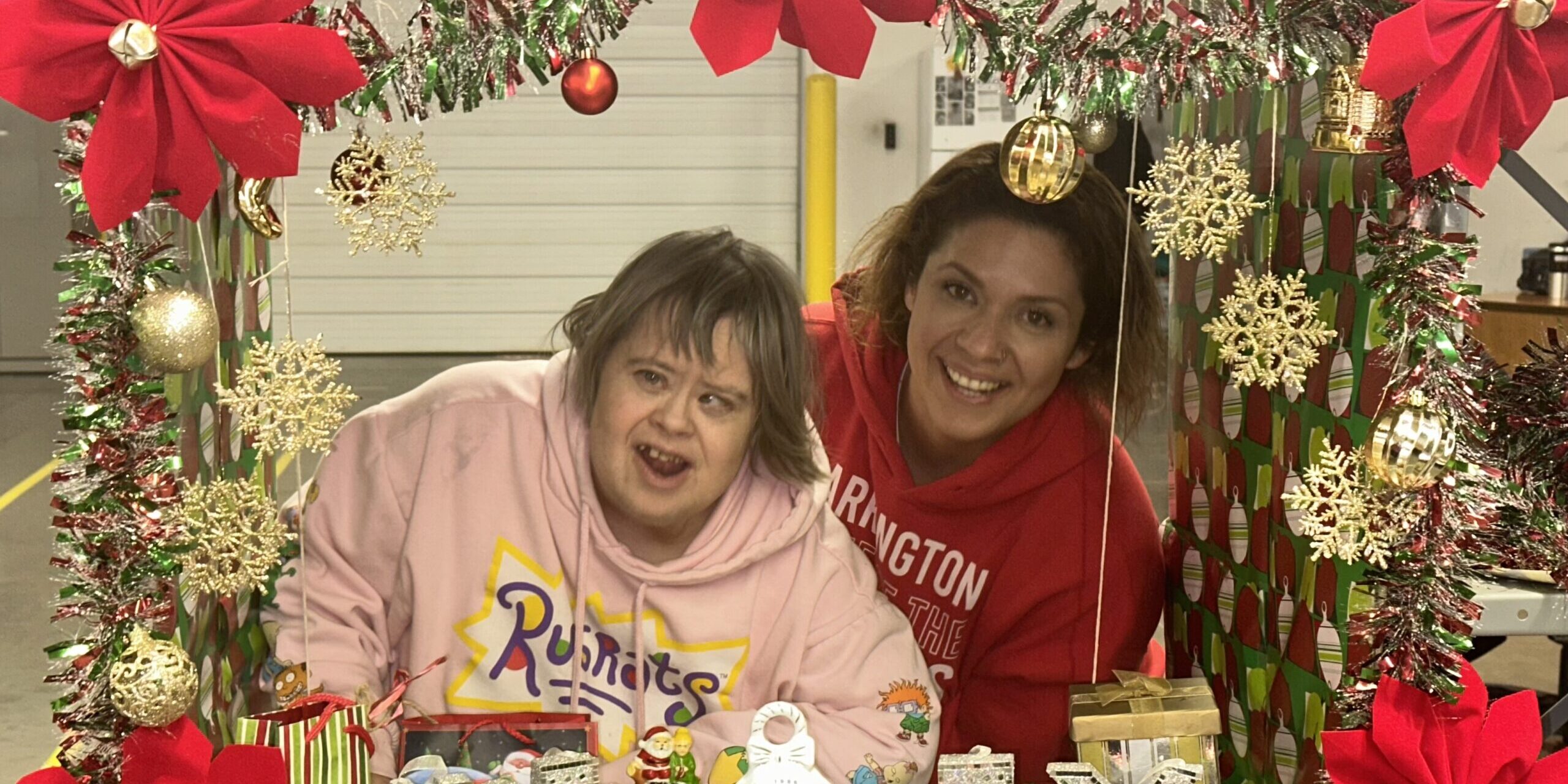 Two individuals posing in a Christmas photo box