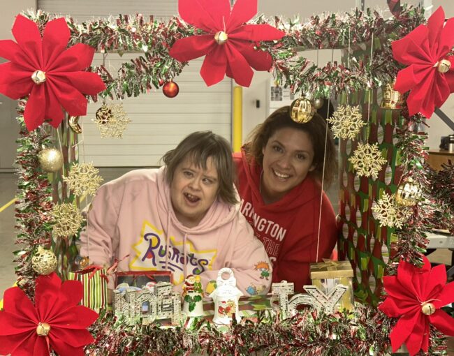 Two individuals posing in a Christmas photo box