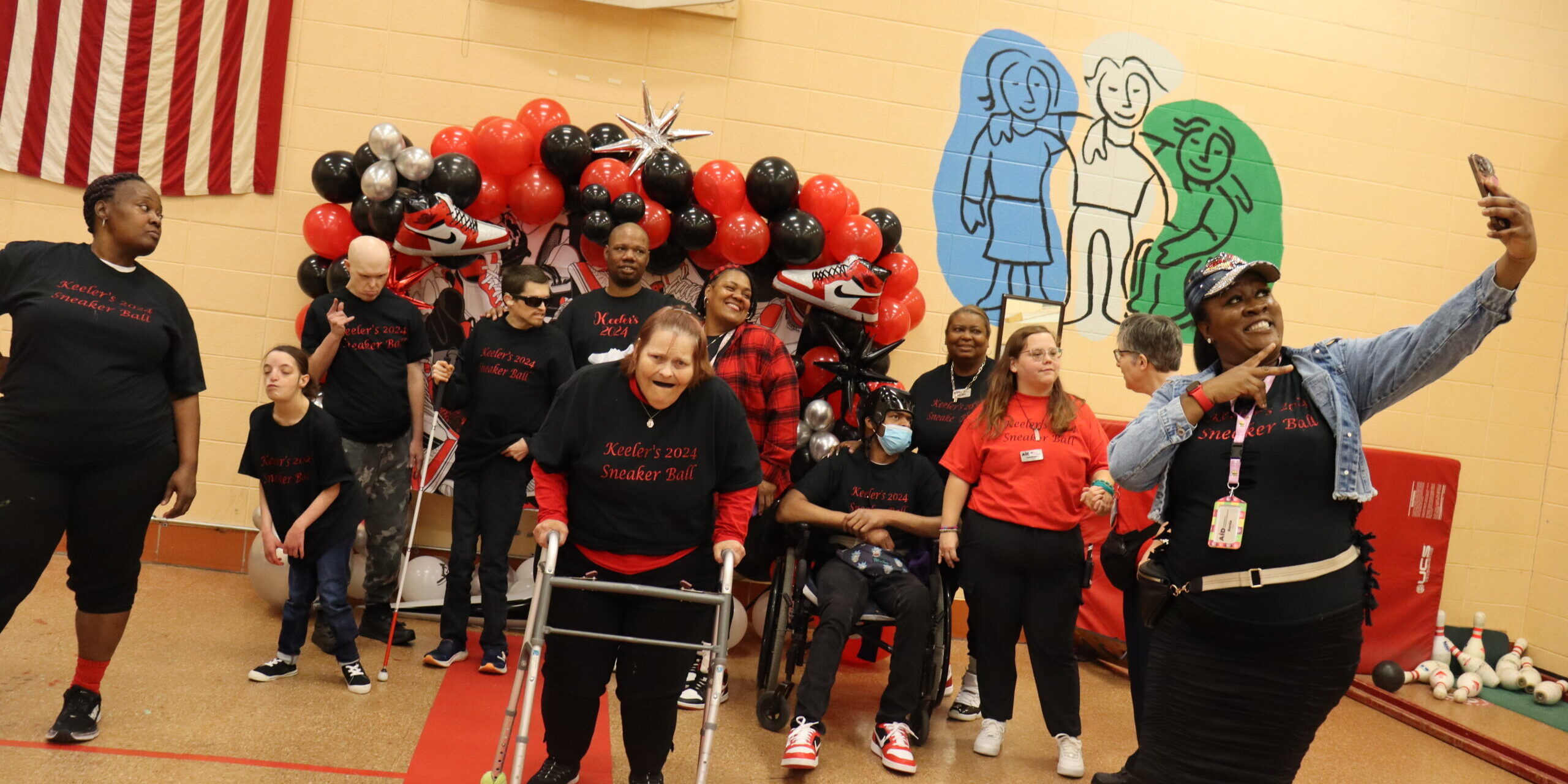 Individuals taking a selfie in front of the Sneaker Ball balloon backdrop