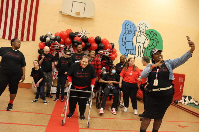 Individuals taking a selfie in front of the Sneaker Ball balloon backdrop
