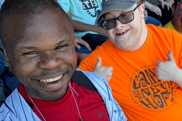 Two men smiling, one giving two thumbs-up